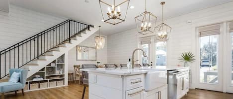 A modern kitchen with a central island, white cabinetry, and pendant lighting.