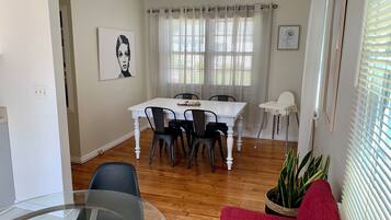A dining area with a white table, black chairs, and a glass table in the foreground.