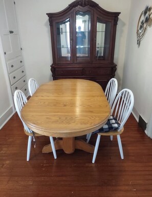A dining table with a wooden top surrounded by white chairs with checkered cushions. - Comfortable 2-bedroom apartment in tranquil Richfield Springs with AC (Richfield Springs)