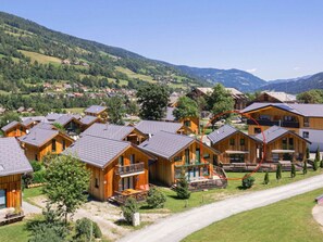 A cluster of wooden cabins with balconies, set in a mountainous area with a clear sky. - One-bedroom Cabin (Sankt Georgen am Kreischberg)