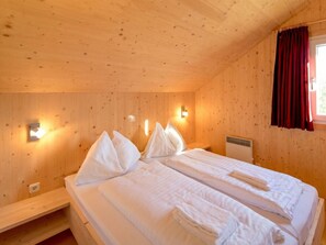 A wooden cabin room with two beds, a bench, and a window with curtains. - One-bedroom Cabin (Sankt Georgen am Kreischberg)