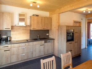 A modern kitchen with wooden cabinets, a black countertop, and a built-in oven. - One-bedroom Cabin (Sankt Georgen am Kreischberg)