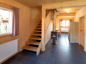 A wooden interior with a staircase, a fireplace, and a view through a window. - One-bedroom Cabin (Sankt Georgen am Kreischberg)
