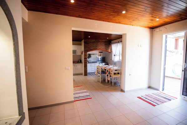 A modern kitchen with a brick accent wall, a dining area with a table and chairs, and a hallway leading to a door.
