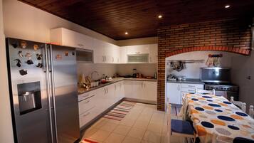 A modern kitchen with white cabinets, a stainless steel refrigerator, a built-in microwave, and a brick wall.