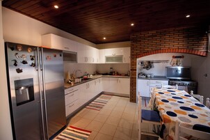 A modern kitchen with white cabinets, a stainless steel refrigerator, a built-in microwave, and a brick wall.