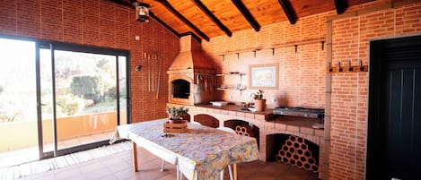 A rustic kitchen with a brick wall, wooden beams, and a tiled floor.
