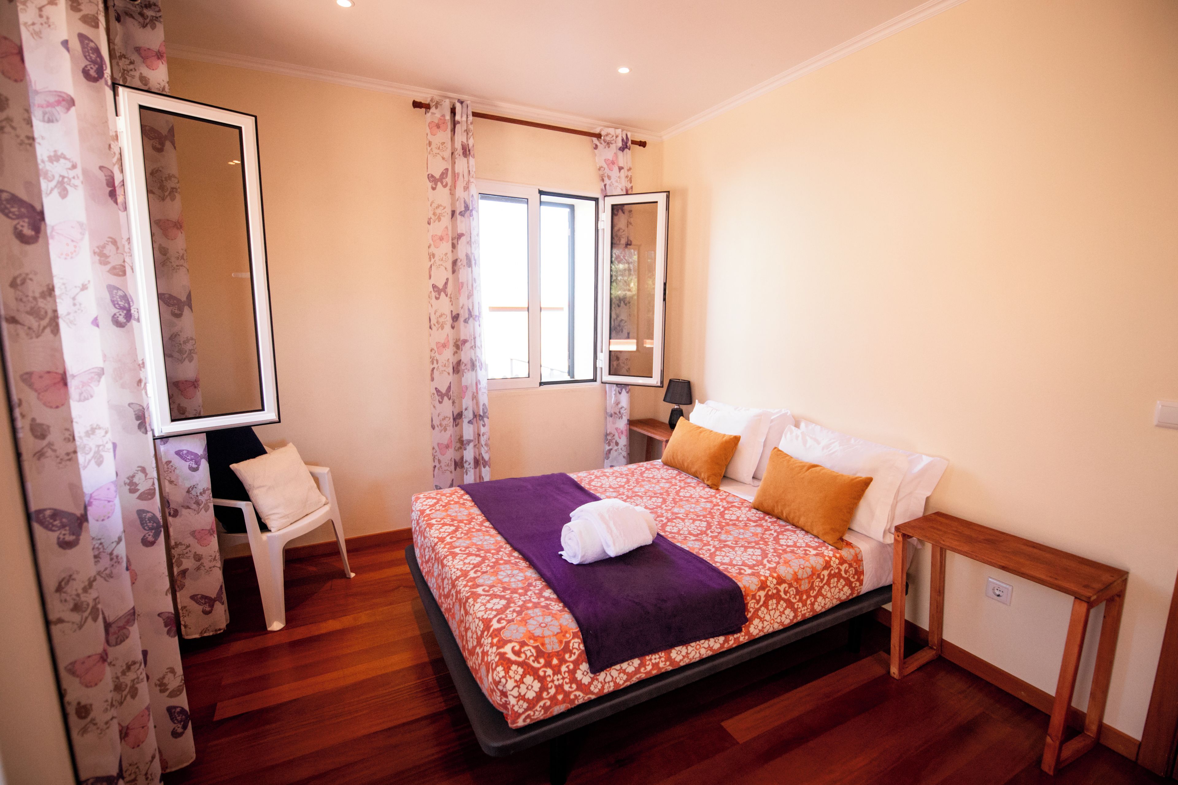 Una habitación de hotel con una cama, una silla, una mesita de noche y un espejo.