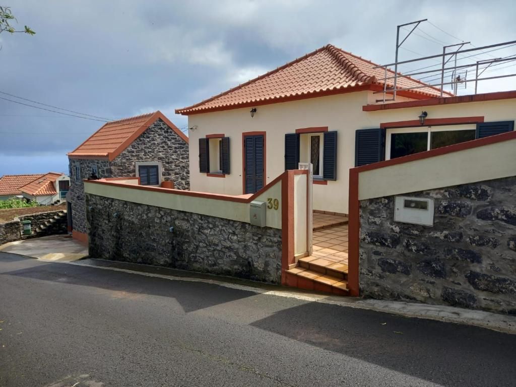 A two-story house with a stone facade, a red-tiled roof, and a number 39 sign.