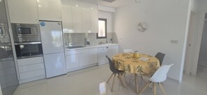Uma cozinha moderna com eletrodomésticos embutidos, uma sala de jantar com mesa redonda e uma janela grande.