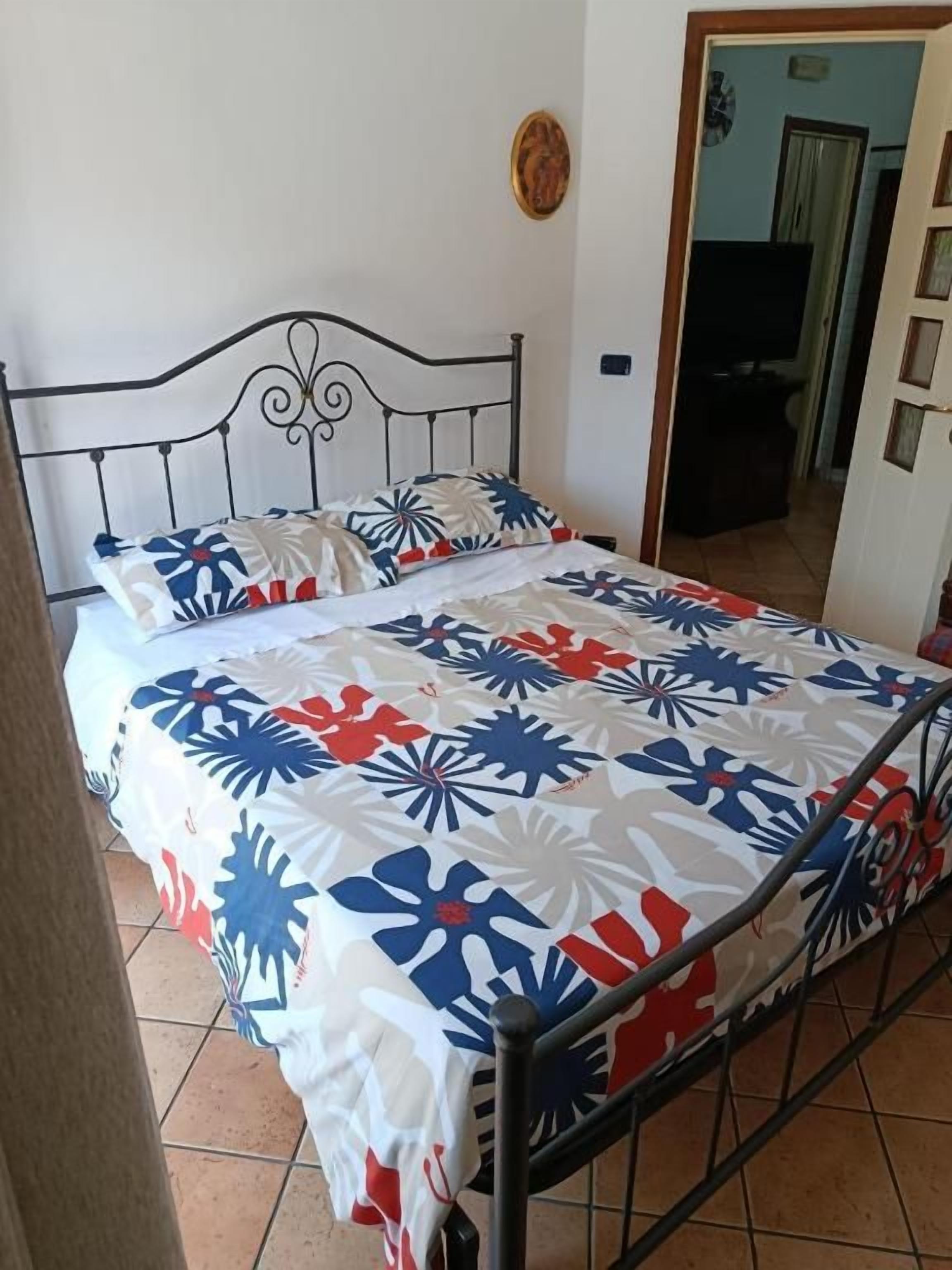 Una cama con estructura metálica y colcha estampada.