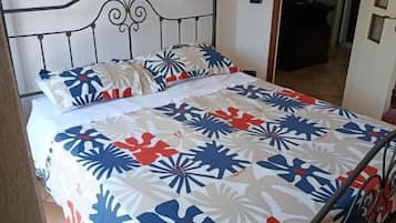 Una cama con estructura metálica y colcha estampada.