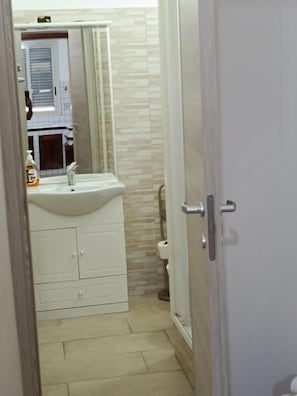 A bathroom with a white sink, mirror, and cabinet.