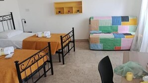 Een kamer met een bed, twee tafels, een stoel en een kleurrijke quilt.