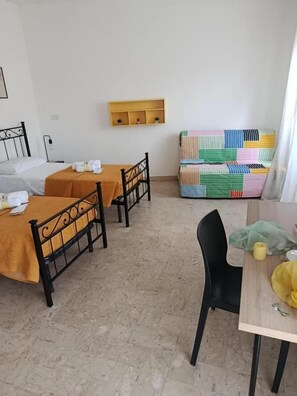 A room with a bed, two tables, a chair, and a colorful quilt. - Misterbeb (Misterbianco)