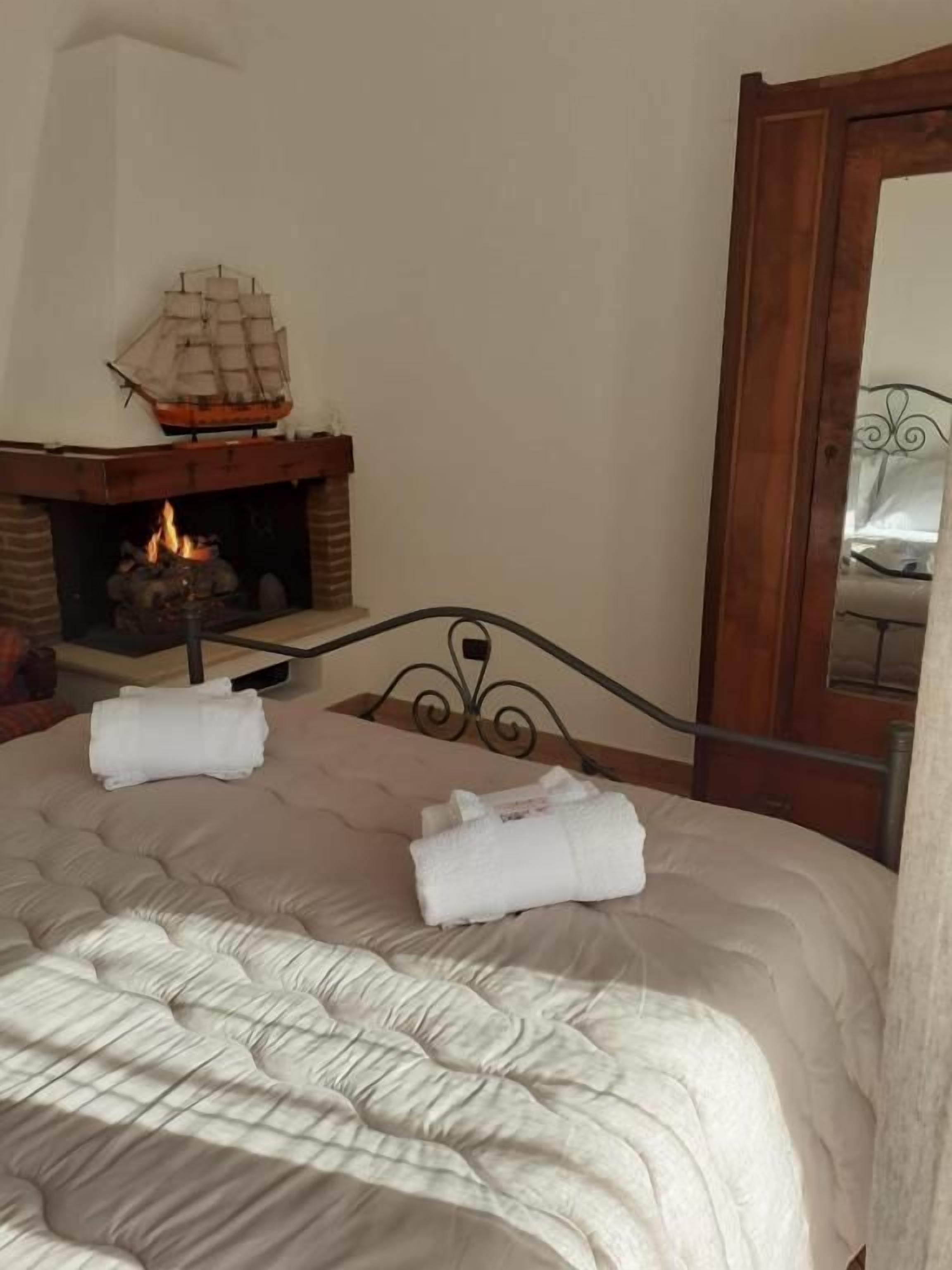 Un dormitorio con cama, chimenea y espejo.