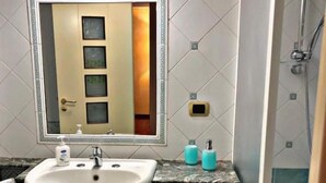 Een badkamer met wastafel, spiegel en douche.