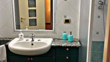 A bathroom with a sink, mirror, and shower.