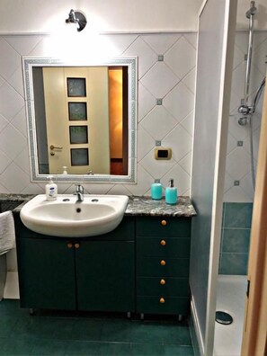 A bathroom with a sink, mirror, and shower. - Misterbeb (Misterbianco)