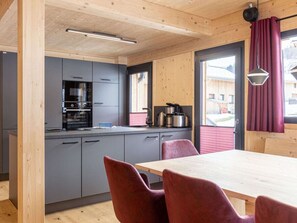 Eine moderne Küche mit grauen Schränken, einem schwarzen Backofen und einem Fenster mit rotem Vorhang.
