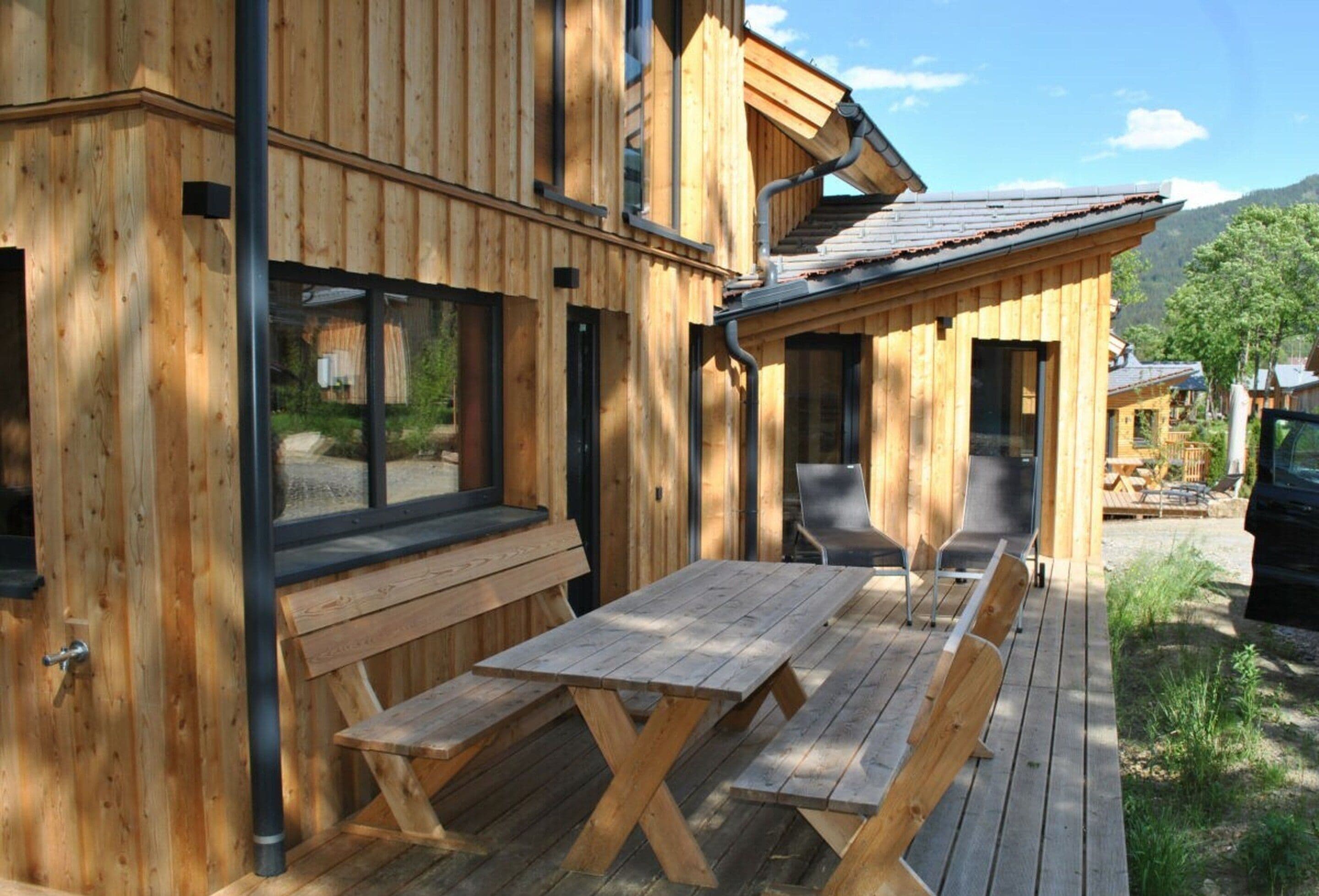 A wooden cabin with a patio area featuring a wooden table and benches.