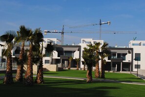 A modern building with a flat roof and a crane in the background. - Groundfloor Oasis Beach VI Oasis Beach (Orihuela)