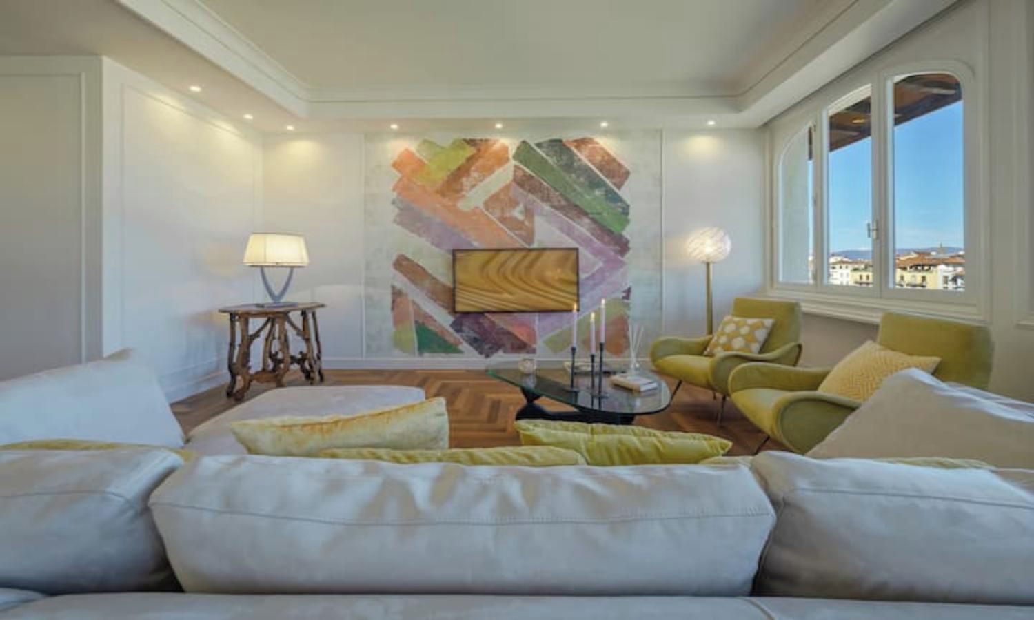 Un salon moderne avec un grand canapé, une table basse et un tableau abstrait aux couleurs vives accroché au mur.