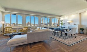 A spacious living room with a large window, a sofa, a dining table, and a kitchen area. - LUXURY FLORENCE APARTMENT WITH PANORAMIC VIEWS & TURKISH BATH (Firenze)