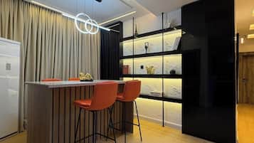 A modern kitchen with a bar area, wooden flooring, and pendant lighting.