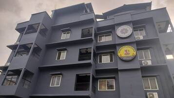 A multi-story building with balconies, air conditioning units, and a restaurant sign.