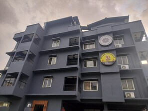 A multi-story building with balconies, air conditioning units, and a restaurant sign. - THE PINWHEEL HOTEL AND RESORTS (Guwahati)