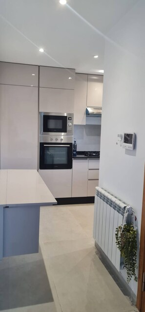Una cocina moderna con horno empotrado, microondas y cocina a gas.