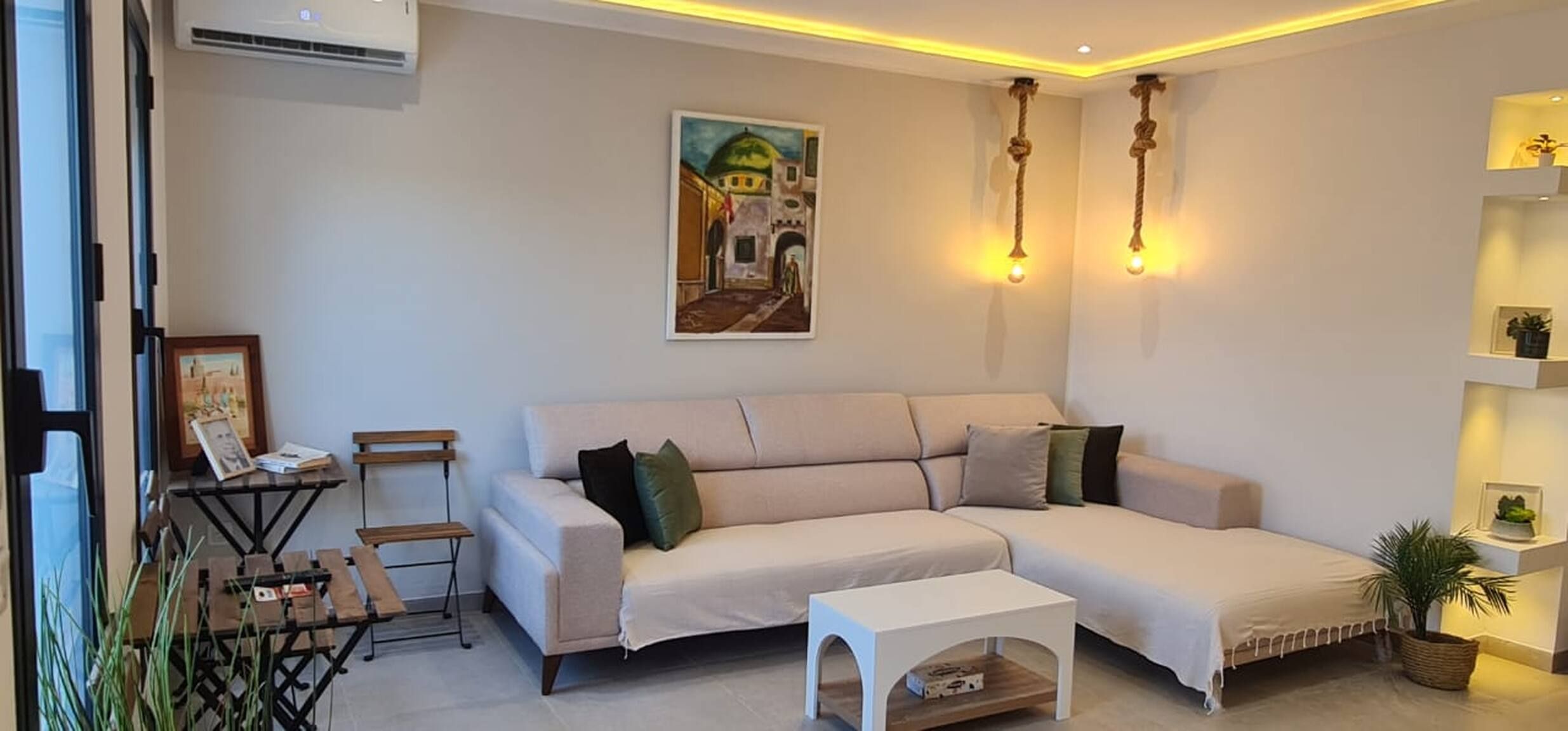 Un salon comprenant un canapé, une table basse, une petite table avec une chaise et un tableau accroché au mur.