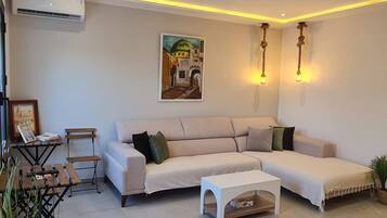 Un salon comprenant un canapé, une table basse, une petite table avec une chaise et un tableau accroché au mur.