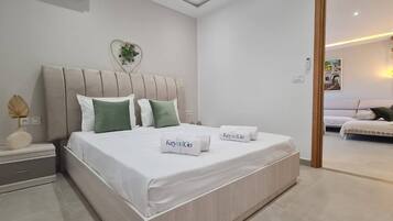 Un dormitorio moderno con una cama, mesitas de noche y vistas a otra habitación.