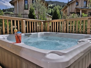 Ein Whirlpool mit Holzterrasse und einem Getränk daneben.