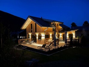 A wooden cabin with a deck, outdoor seating, and a grill area. - One-bedroom Cabin (Sankt Georgen am Kreischberg)