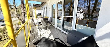 A covered outdoor area with a table and chairs, large windows, and a view of the surrounding landscape.