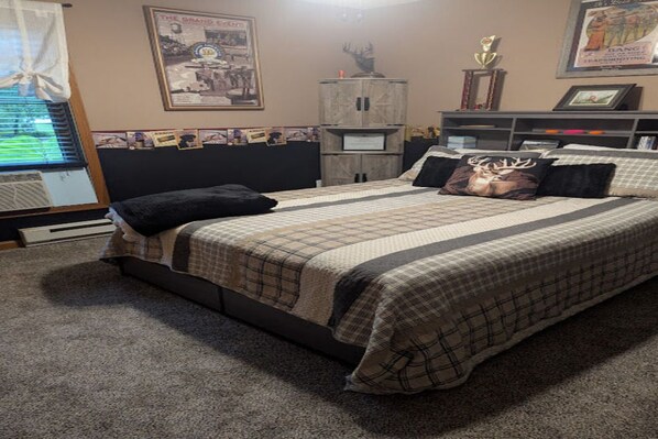 Een slaapkamer met een bed, een dressoir, een kast en wanddecoraties.