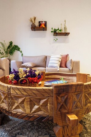A living room with a wooden coffee table, a sofa, and a wall-mounted shelf with decorative items. - CASA CAOBA - Modern colonial Villa, 3 volcano views rooftop & 4BR (Antigua)