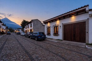 A cobblestone street lined with buildings, a mountain in the background, and parked cars. - CASA CAOBA - Modern colonial Villa, 3 volcano views rooftop & 4BR (Antigua)