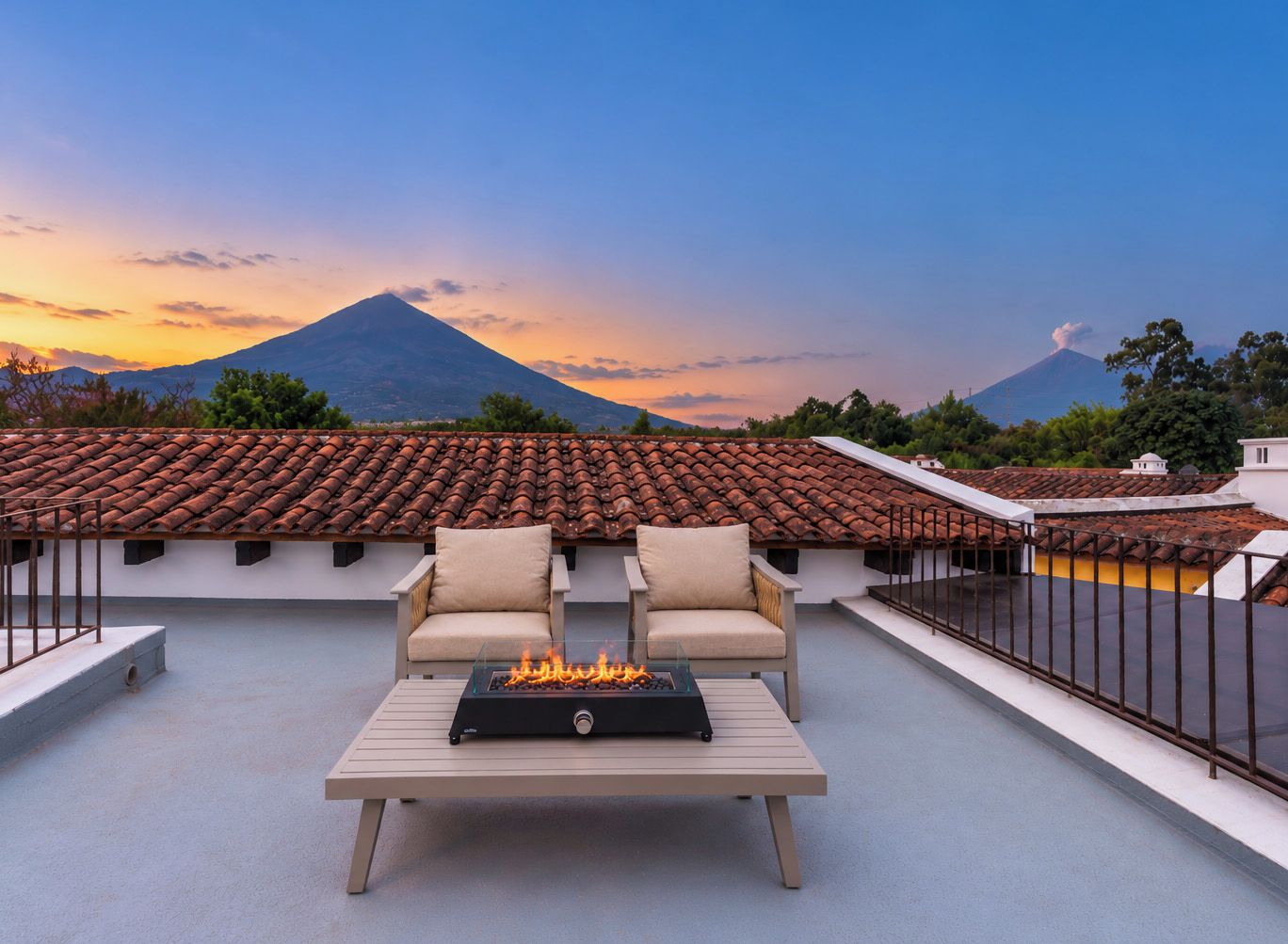 Una terrazza sul tetto con una focolare, due sedie e vista su una montagna.
