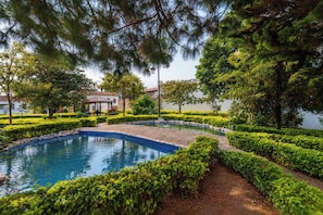 A landscaped garden with a circular pool, neatly trimmed hedges, and a gazebo. - CASA CAOBA - Modern colonial Villa, 3 volcano views rooftop & 4BR (Antigua)