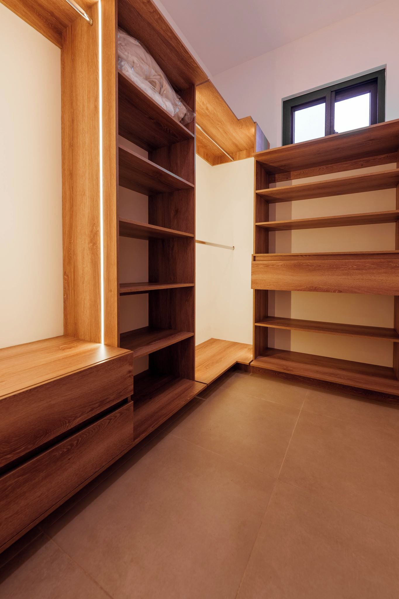 A wooden built-in closet with multiple shelves and a sliding door.