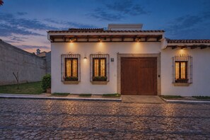 A building with a tiled roof, a wooden door, and two windows with flower boxes. - CASA CAOBA - Modern colonial Villa, 3 volcano views rooftop & 4BR (Antigua)
