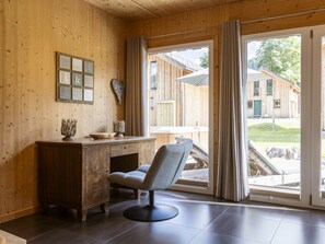 A room with wooden walls, a desk with a chair, and a large window with curtains. - One-bedroom Cabin (Sankt Georgen am Kreischberg)