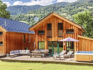 A wooden cabin with a deck, outdoor seating, and a hot tub. - One-bedroom Cabin (Sankt Georgen am Kreischberg)