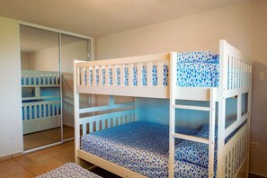 Ein Stockbett mit gemustertem Lattenrost, eine Schiebetür und ein kleiner Teppich auf dem Boden.