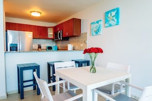 Eine moderne Küche mit Holzausstattung, Edelstahlgeräten und einem Essbereich mit weißem Tisch und blauen Stühlen.