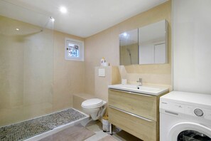 Un bany compacte amb dutxa, vàter, rentapla i rentamàquines.